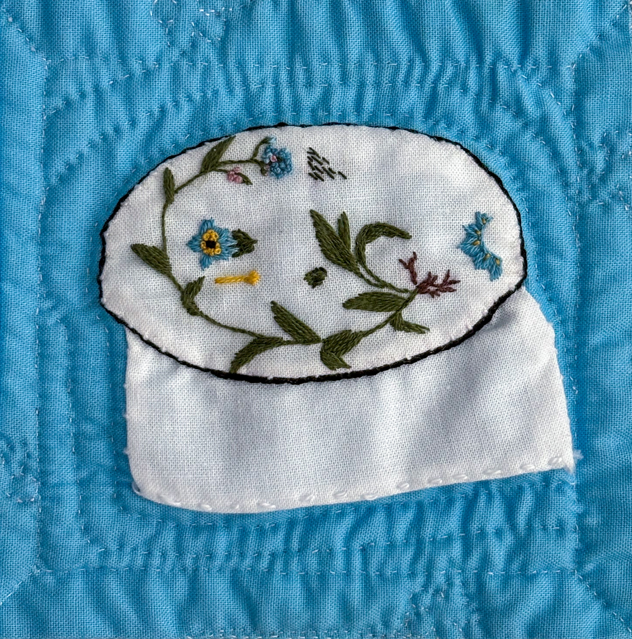 Forget me not botanical embroidery on white cotton, appliquéd on blue cotton to depict fabric in an embroidery hoop.